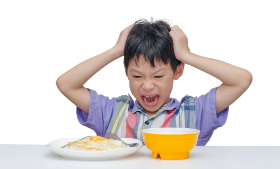 boy screaming at food at table